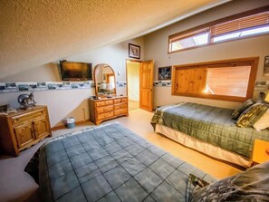 Un dormitorio con dos camas, un aparador, un espejo, un televisor y una ventana con persianas.