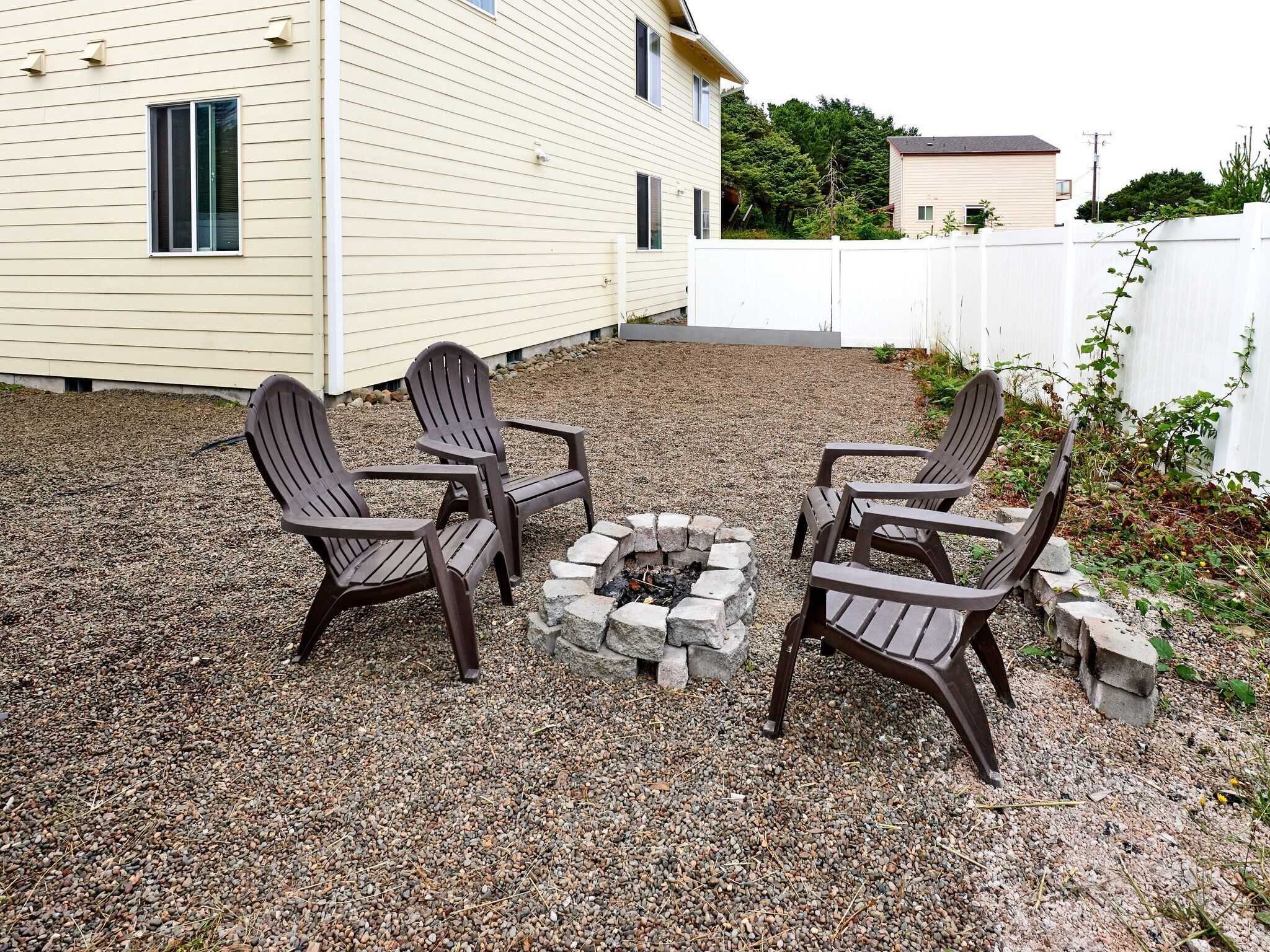 Un espace extérieur aménagé avec des chaises Adirondack et un foyer en pierre.