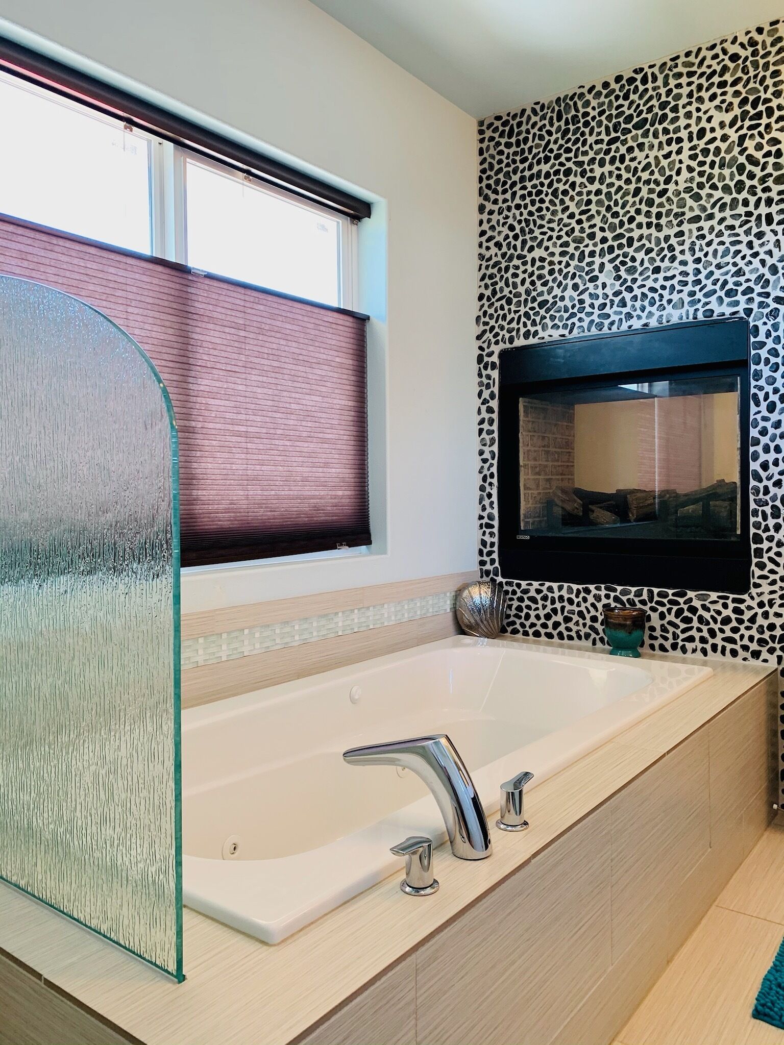 Une salle de bain moderne avec une grande baignoire, une paroi en verre, un mur à motifs léopard et un téléviseur fixé au mur.