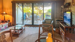 Un salon spacieux doté d’une porte-fenêtre coulissante donnant sur un balcon, aménagé avec des chaises et une table.