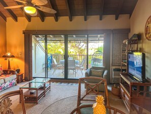 Een ruime woonkamer met een schuifglazen deur die uitkomt op een balkon, ingericht met stoelen en een tafel.