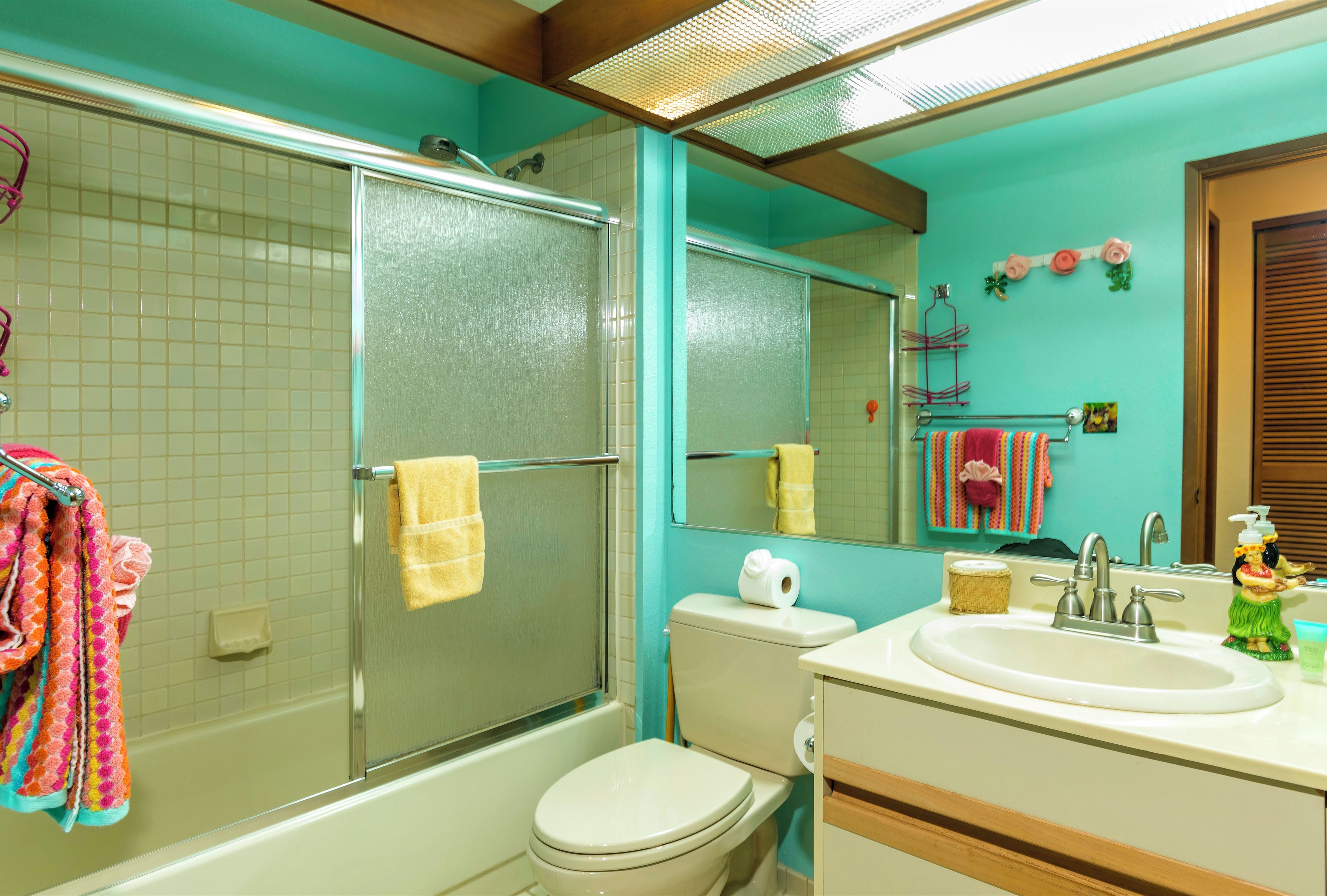 A bathroom with a shower, toilet, sink, and mirror.