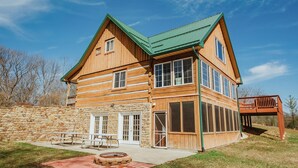 A wooden cabin with a stone wall, large windows, and a picnic table. - Log Cabin, Hot Tub, Fire Pit, Near Yellowwood (Nashville)