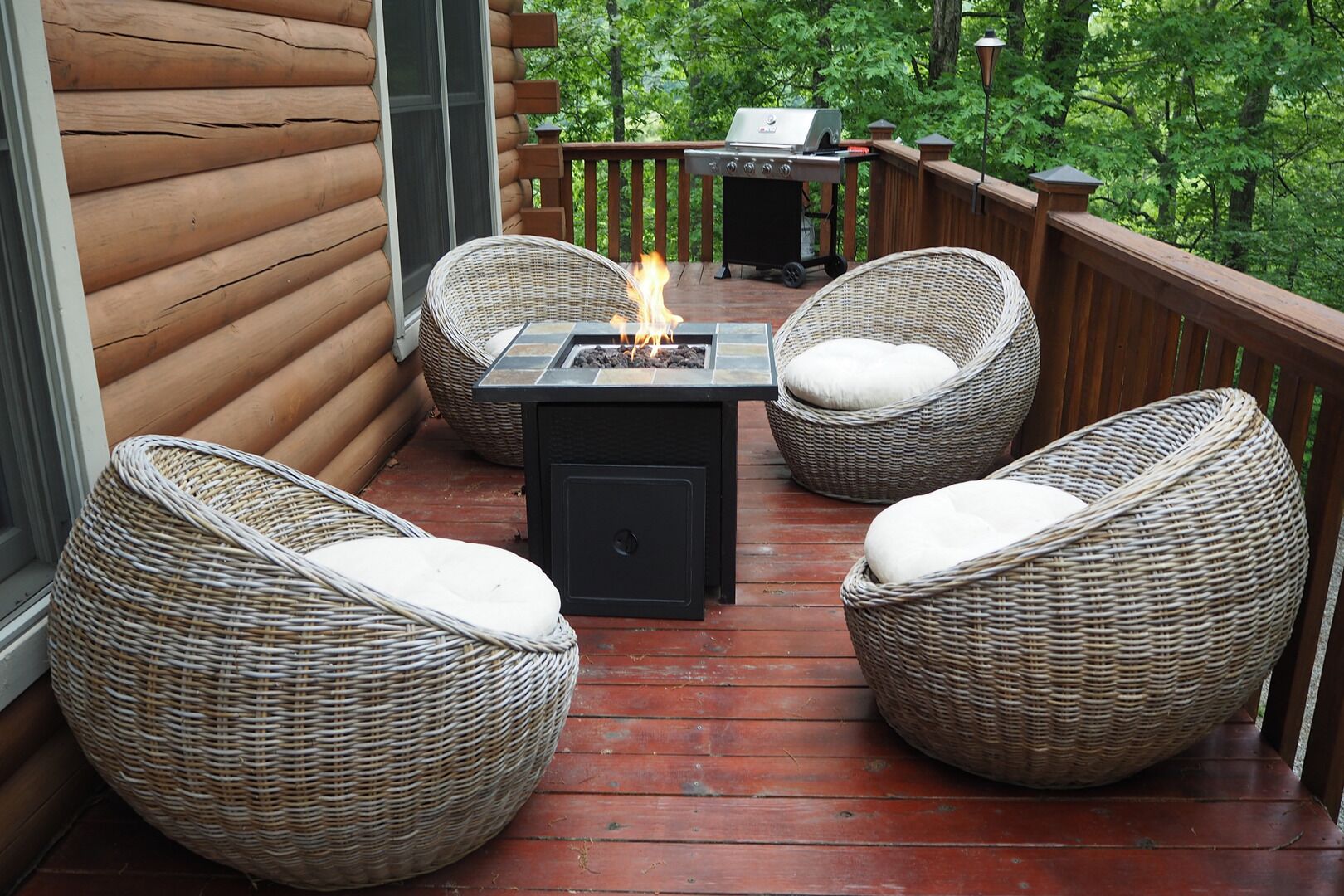 Een terras met rieten stoelen, een vuurkorf en een barbecue.
