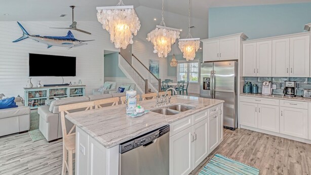 A modern kitchen with a central island, stainless steel appliances, and a dining area with a wooden table and chairs.