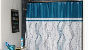 Une salle de bain avec un rideau de douche bleu et blanc, un bol en verre, une bouteille et un panneau d’encouragement accroché au mur.