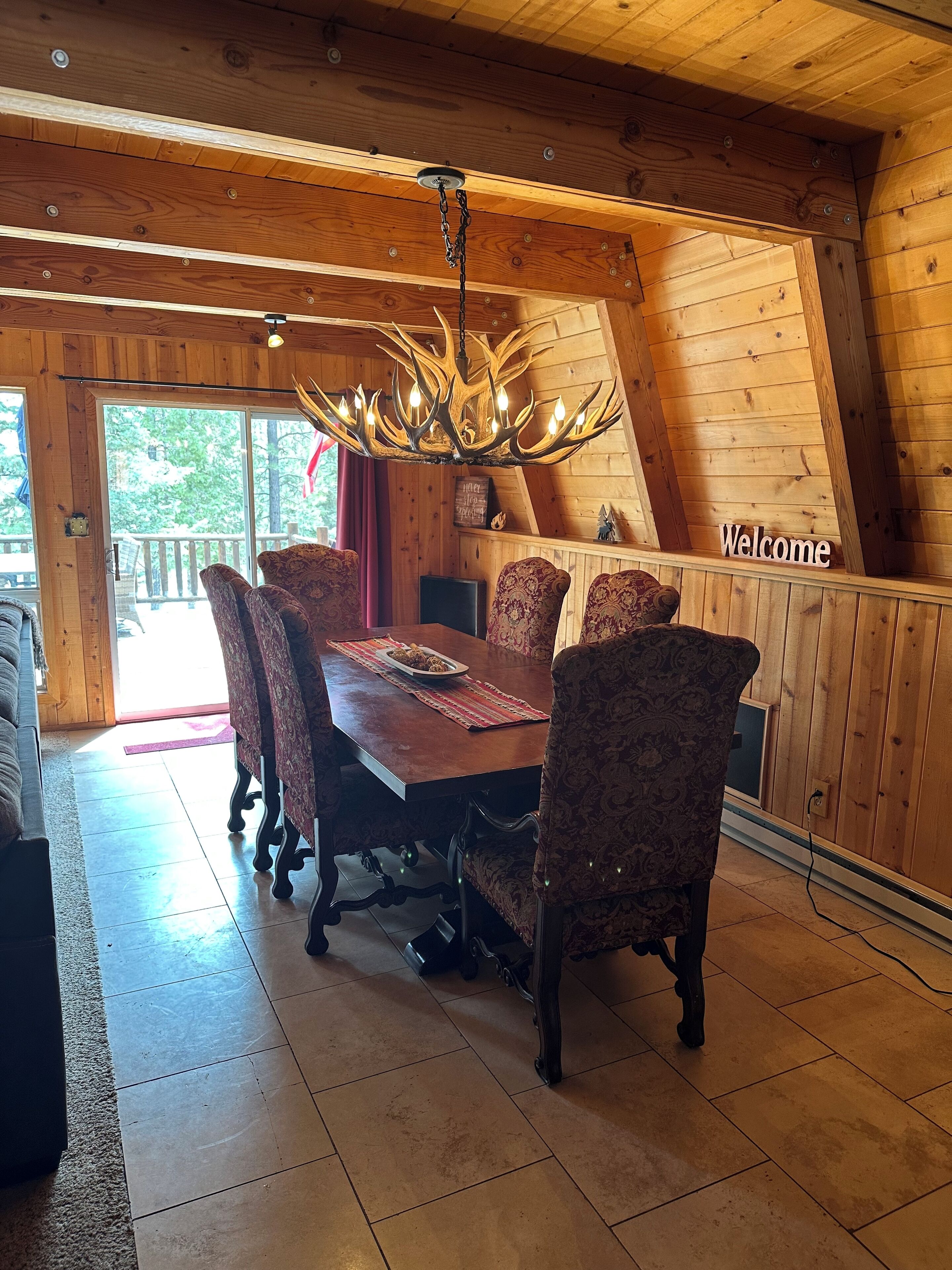 Un interior de madera con una mesa de comedor, sillas estampadas y una araña.