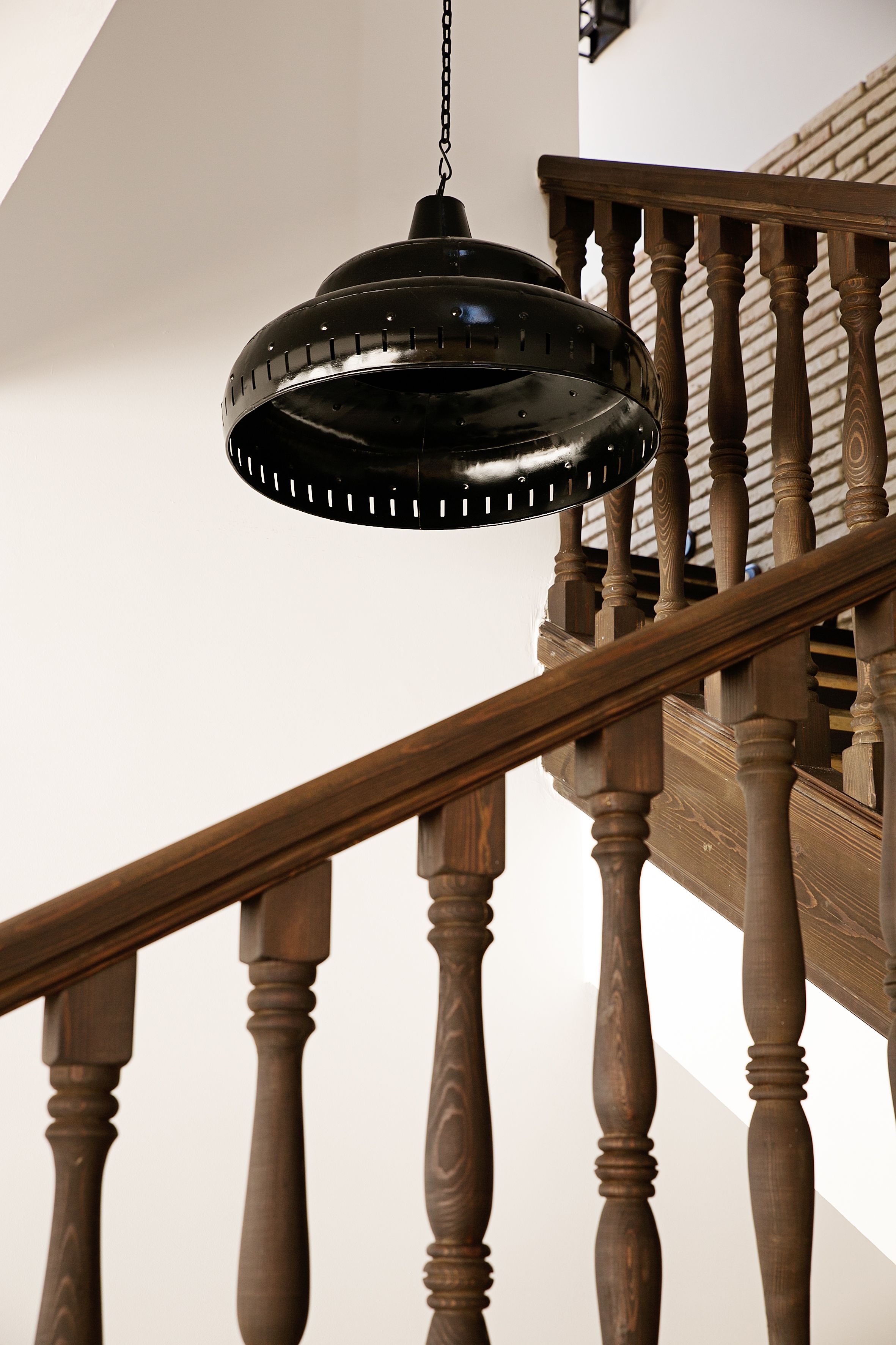 A wooden staircase with a black pendant light hanging from the ceiling.