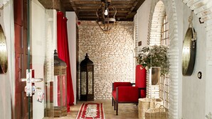 Un interior acogedor con una pared de piedra, una silla roja y una puerta de cristal que da a una cortina roja.