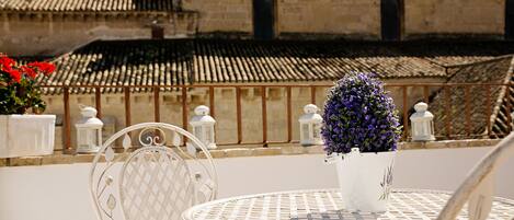 A white metal table and chairs set outdoors with a potted plant on the table.