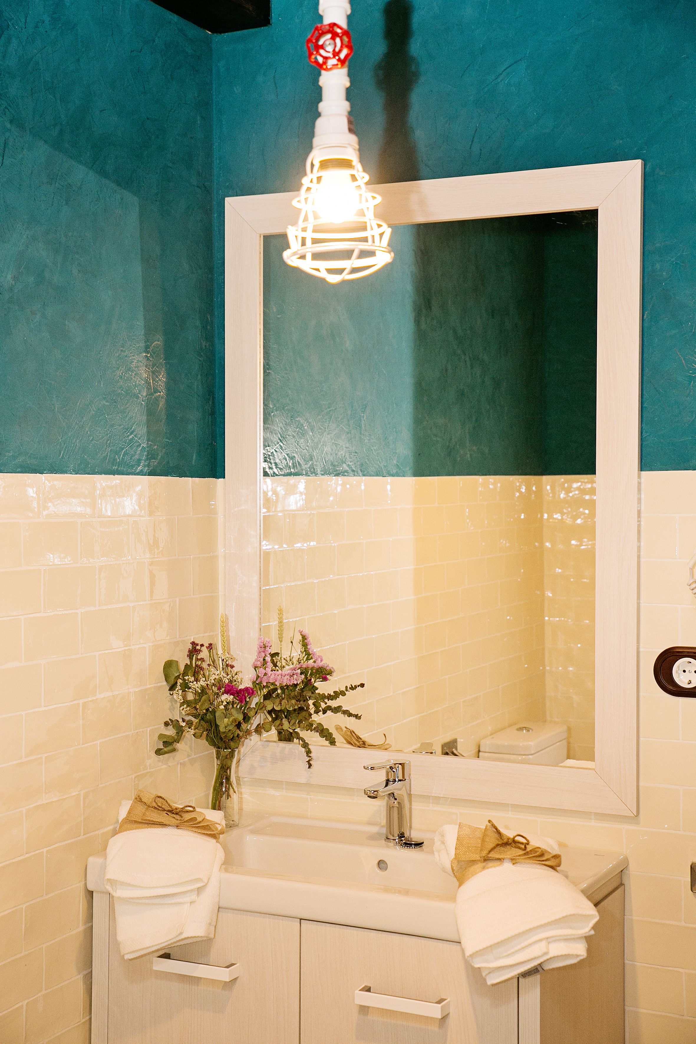 Un baño con lavamanos, espejo y toallero.