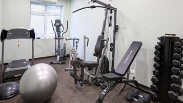 A gym with exercise equipment, a stationary bike, and a large exercise ball.