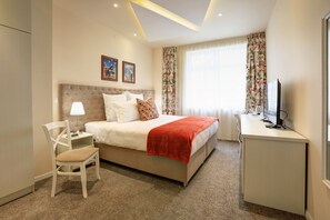 A hotel room with a bed, a desk, a chair, a television, and a window with curtains.