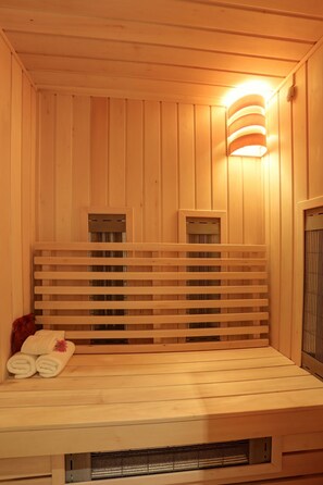 Una sauna con paredes de madera, un banco y una lámpara fijada a la pared.