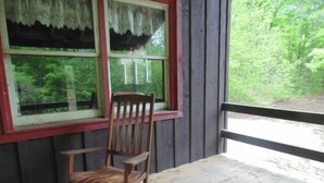A wooden rocking chair on a porch with a view of a forest. - Adirondack Rustic 2 Story- 10 ACRES-SKI, SKI, SKI! (Warrensburg)