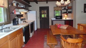 A kitchen with wooden cabinets, a wooden dining table with benches, a microwave, and a refrigerator. - Adirondack Rustic 2 Story- 10 ACRES-SKI, SKI, SKI! (Warrensburg)