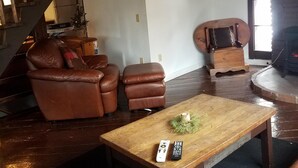 A cozy living room with a wooden coffee table, leather sofas, and a fireplace. - Adirondack Rustic 2 Story- 10 ACRES-SKI, SKI, SKI! (Warrensburg)