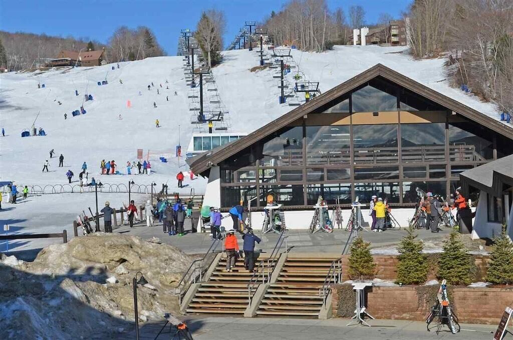 Ein Skigebiet mit einem großen Gebäude, Skipfächern und Skifahrern.