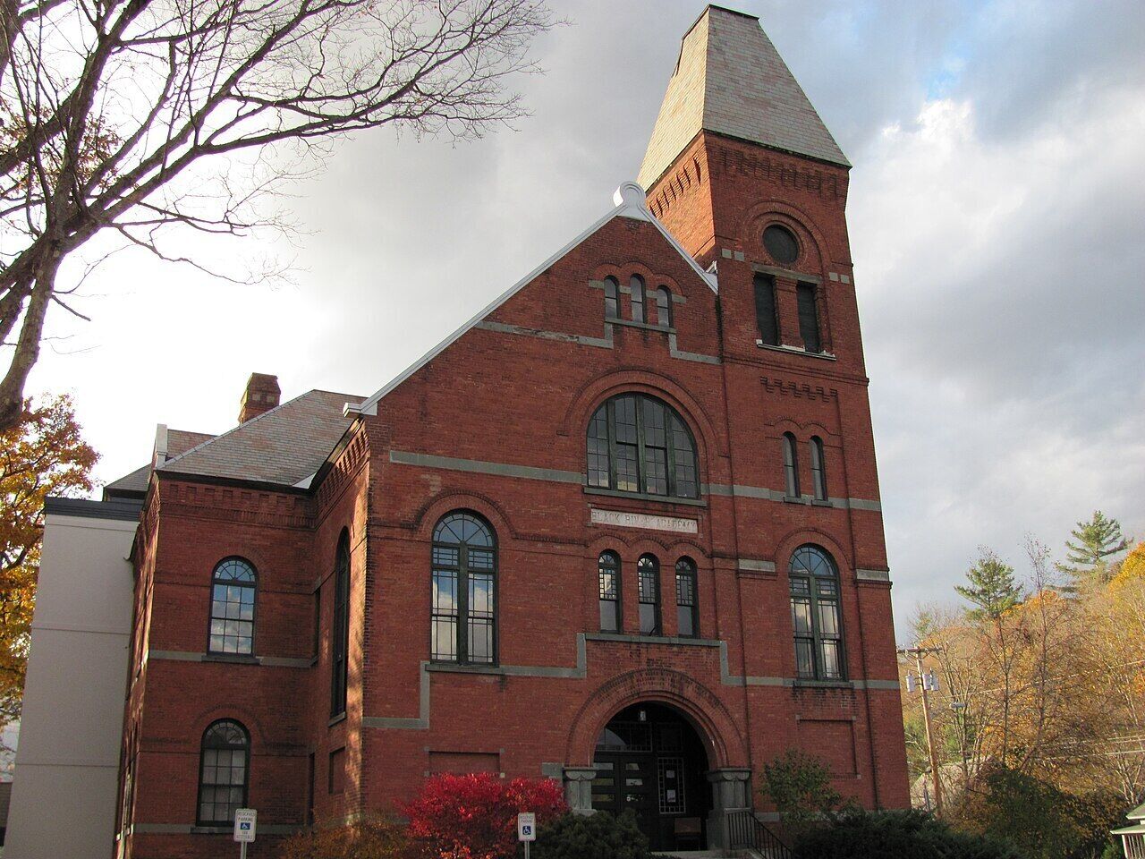 A red brick building with a prominent tower, large arched windows, and a central entrance.