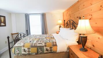 Une chambre à coucher avec une tête de lit en bois, une couvre-lit matelassée, deux lampes de chevet, une commode en bois et une fenêtre avec des rideaux.