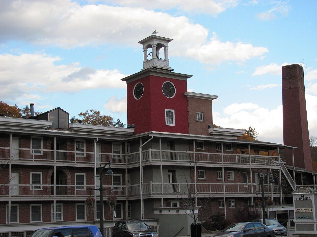 A multi-story building with a prominent clock tower, balconies, and a chimney.