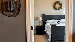 A bedroom with a bed, nightstand, lamp, and a wall-mounted wreath.
