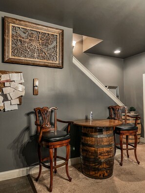 A room with a wooden table and chairs, a barrel, a staircase, and a framed map on the wall. - Indulge in Relaxation:King Bed Suite with Park Access for Your Ultimate Getaway! (Nashville)