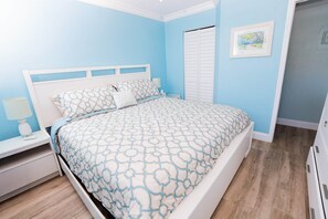 A bedroom with a bed, nightstand, and a door.