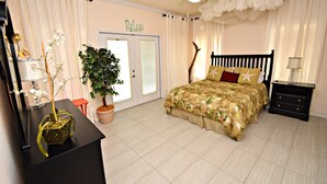 Une chambre à coucher avec un lit, une table de chevet, une plante en pot, un bureau et une porte.