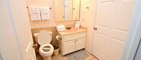 Een badkamer met toilet, wastafel, spiegel en handdoekhouder.