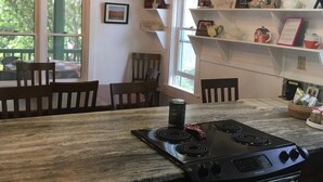 Een keuken met een granieten aanrecht, een zwarte kookplaat en een eethoek met houten stoelen.
