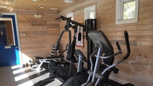 Een sportschool met diverse fitnessapparaten, een blauwe deur waarop 