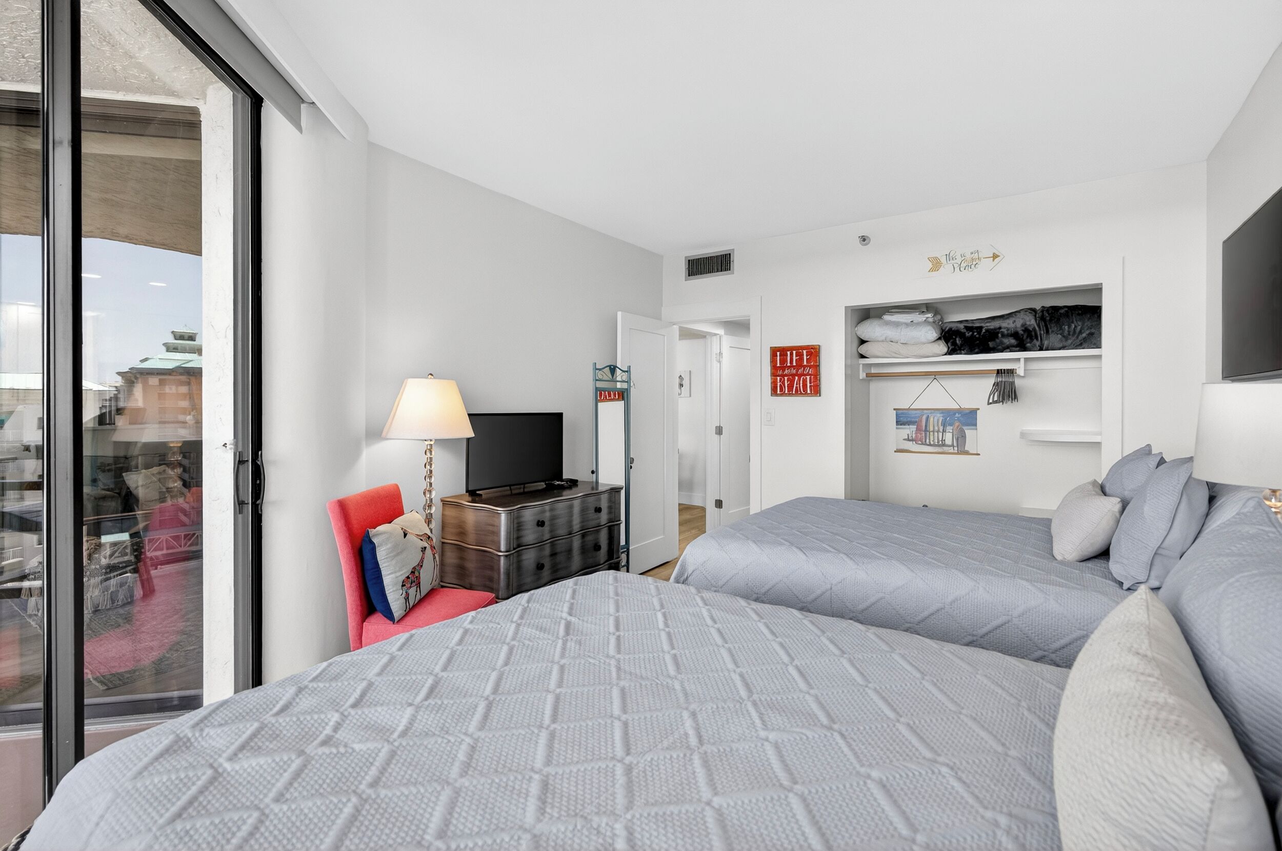 Hotellihuone, jossa on kaksi sänkyä, televisio, lipasto ja näkymä kaupunkiin.