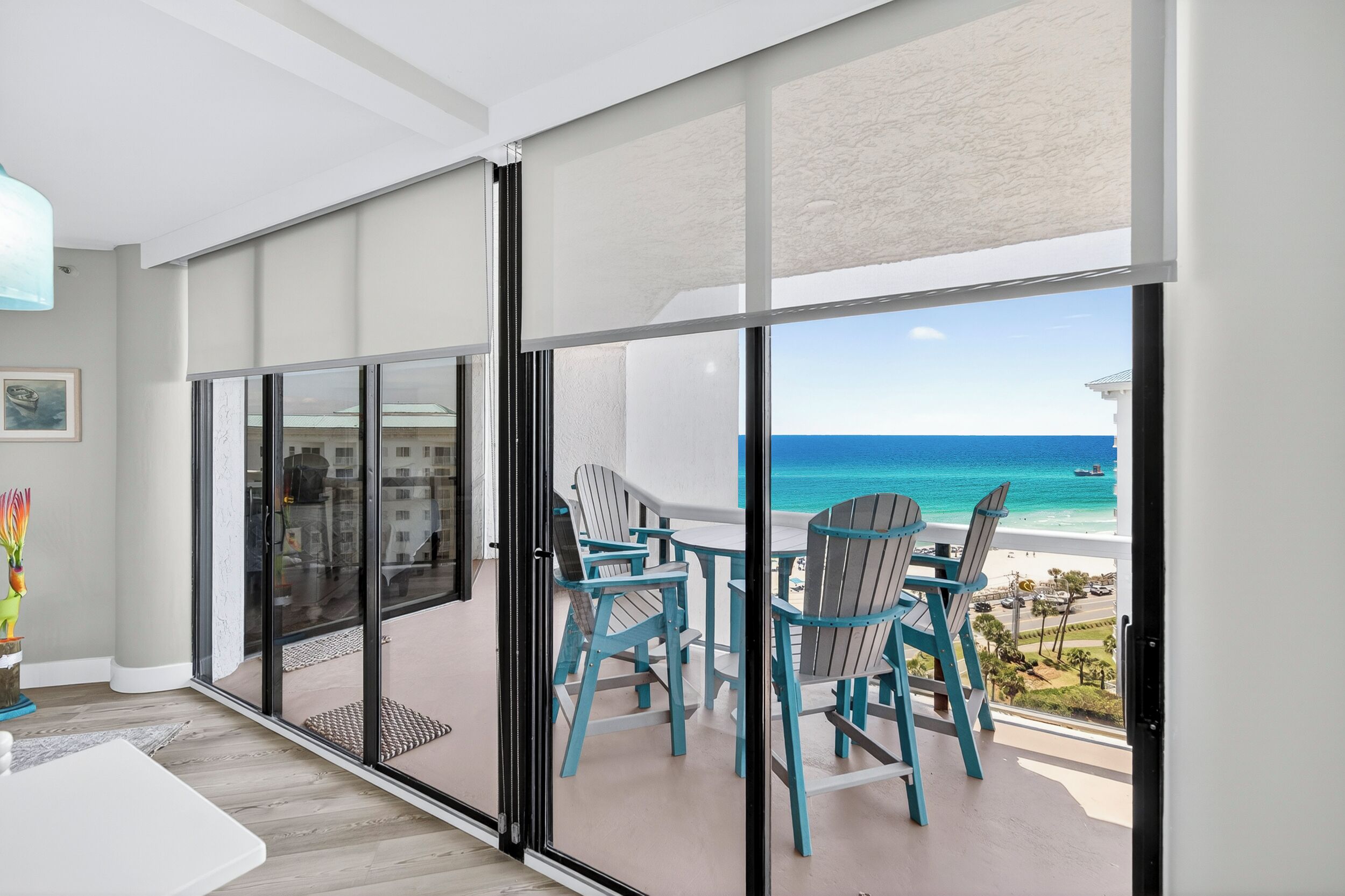 Un balcon avec vue sur l’océan, une table avec des chaises et une porte-fenêtre coulissante.
