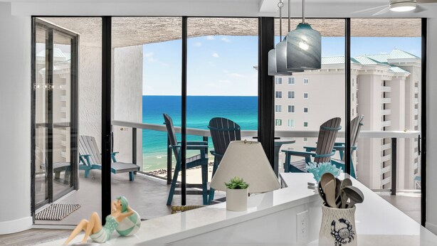 Ein Balkon mit Meerblick, Stühlen, einer Lampe und einer kleinen Pflanze.