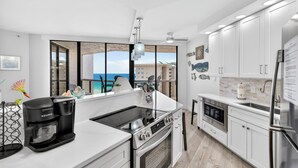 Eine moderne Küche mit Kaffeemaschine, Backofen und Blick auf den Ozean.