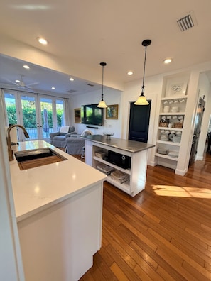 A modern kitchen with a central island, built-in shelving, and pendant lighting.