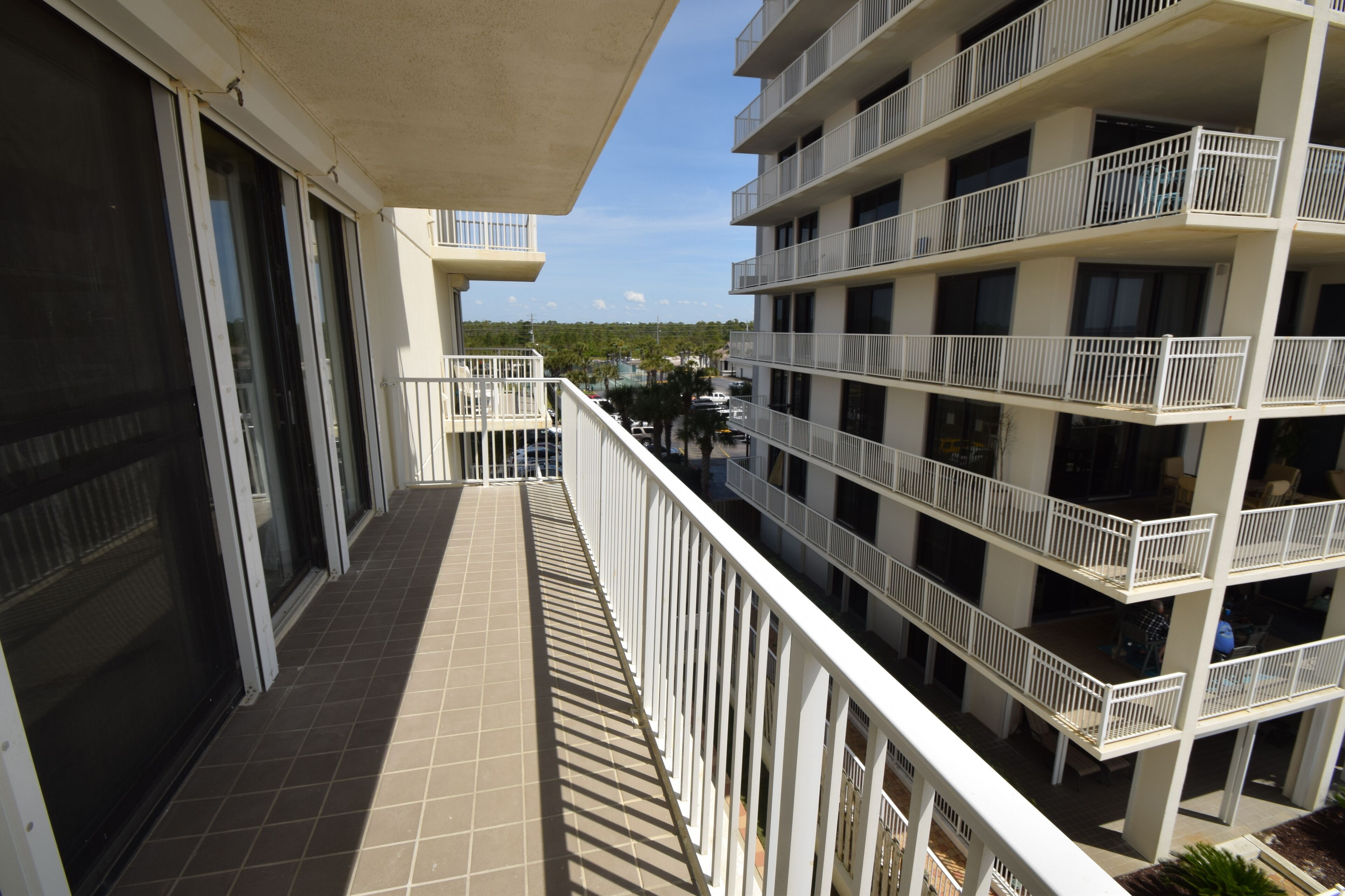 A multi-story building with balconies, a tiled floor, and a clear view of the street below.