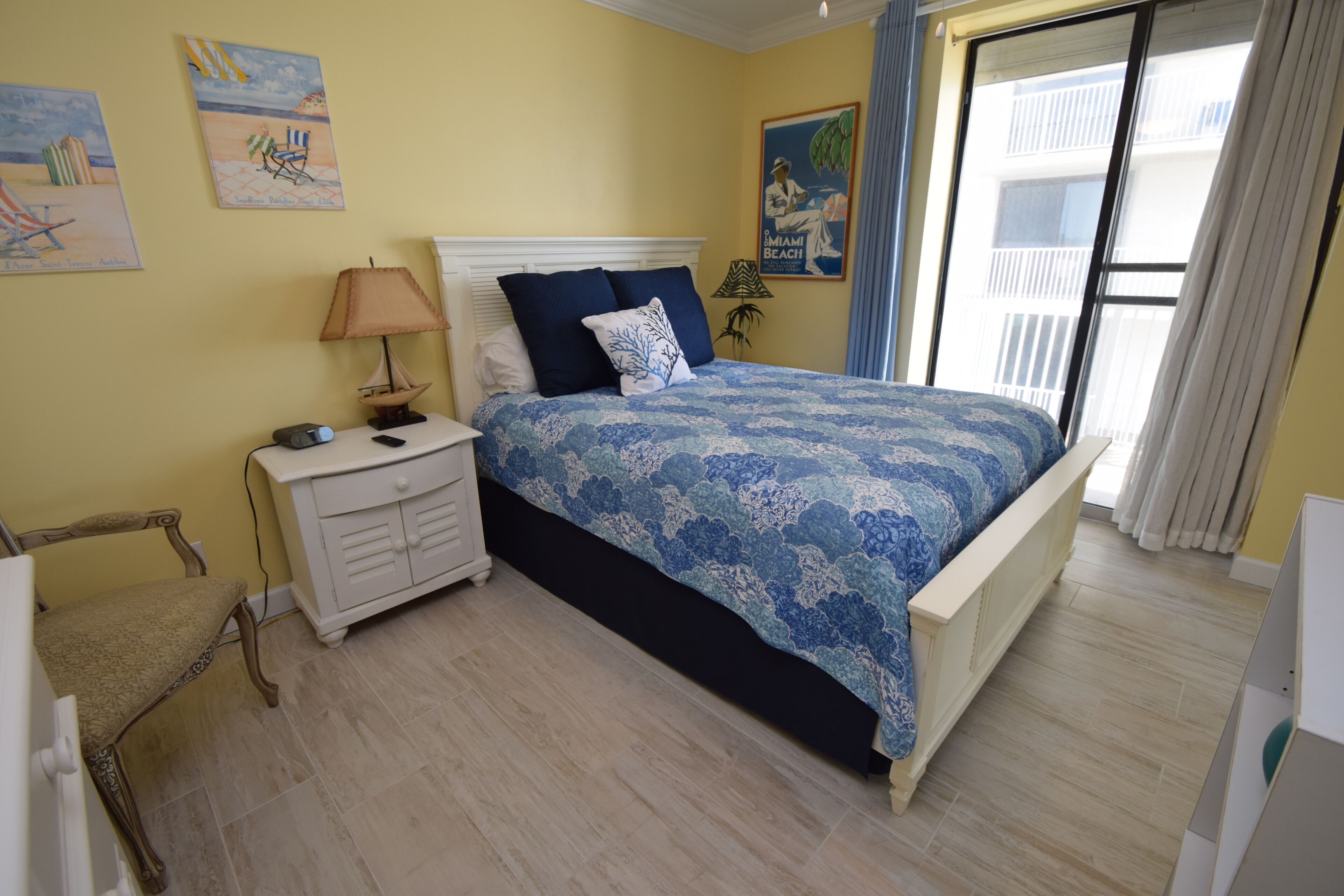 A bedroom with a bed, nightstand, lamp, and artwork on the wall.