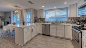 A modern kitchen with white cabinetry, a central island, and a built-in dishwasher. - Fabulous 4 Bedroom Home + Free Private Heated POOL (Glendale)