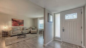A living room with a sofa, two armchairs, a coffee table, and a painting on the wall. - Fabulous 4 Bedroom Home + Free Private Heated POOL (Glendale)