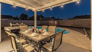 An outdoor patio with a pool, a barbecue grill, and a dining table set for four. - Fabulous 4 Bedroom Home + Free Private Heated POOL (Glendale)