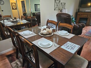 A dining room with a wooden table set for four, surrounded by chairs. - Walk-In Shower/ NEW Decor/ Kings/ CLEAN/ Indoor-Outdoor Pools/ Golf View on 10th (Branson)