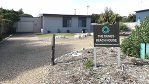 A sign for The Dunes Beach House with a modern building in the background. - Dunes Beach House Goolwa Beach (Goolwa)