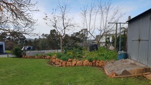 A well-maintained backyard with a grassy lawn, a stone border, and various plants.