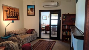 A living room with a sofa, a rug, a bookshelf, and a door leading outside.