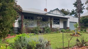 A house with a front porch, a garden with various plants, and a number '30' displayed on the wall.