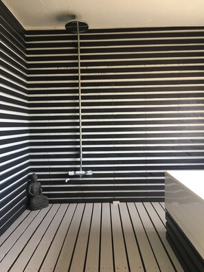 Uma casa de banho moderna com parede listrada em preto e branco, chão de madeira e uma estátua de Buda.