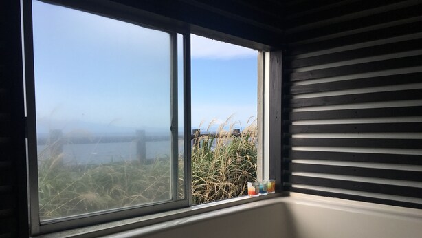 Ein Zimmer mit großem Fenster und Blick auf ein Gewässer und Vegetation.