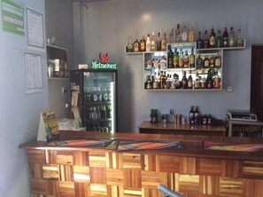 Eine Bar mit einer Holztresen, einem Heineken-Kühlschrank und Regalen voller verschiedener Spirituosen.